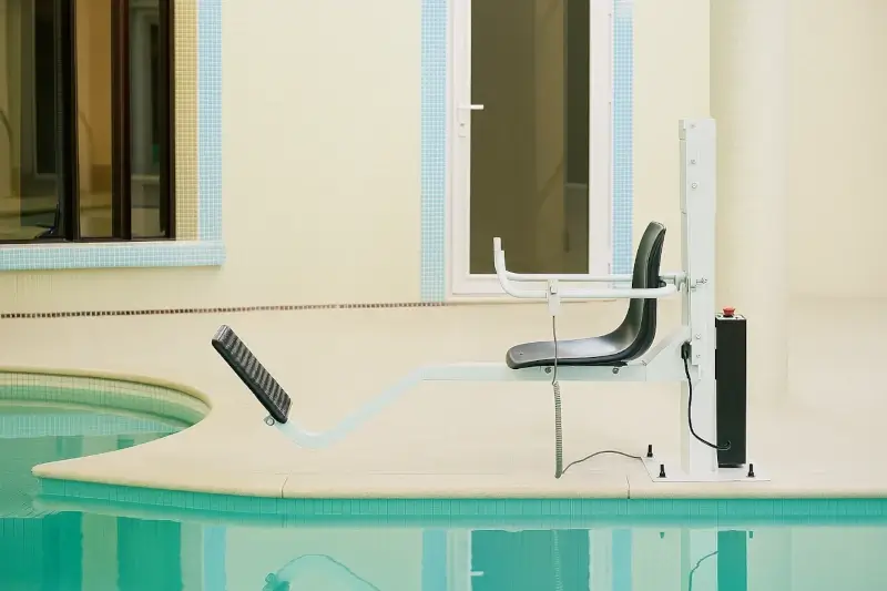 Modern-design pool lift with safe seat beside a bright-tiled indoor swimming pool