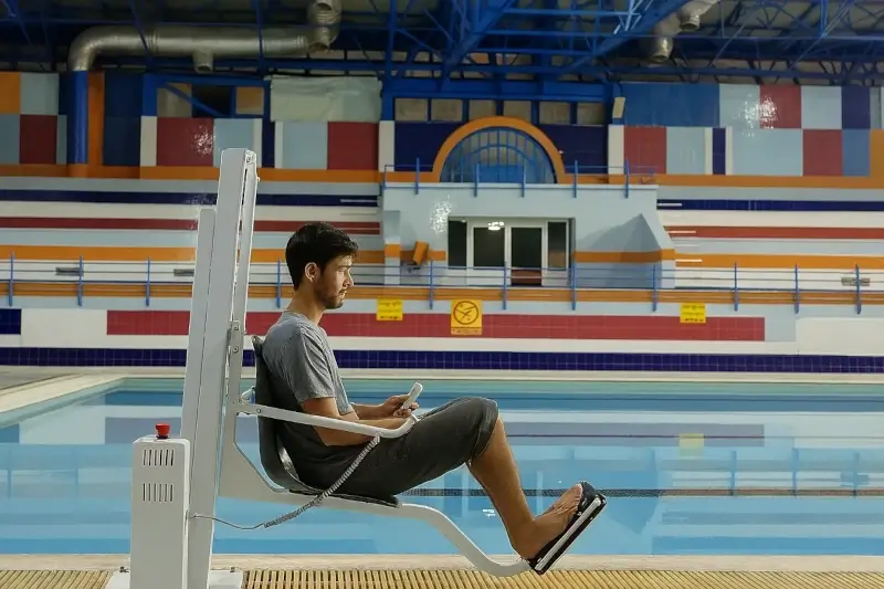 Pool lift in a public indoor swimming facility with colorful wall design
